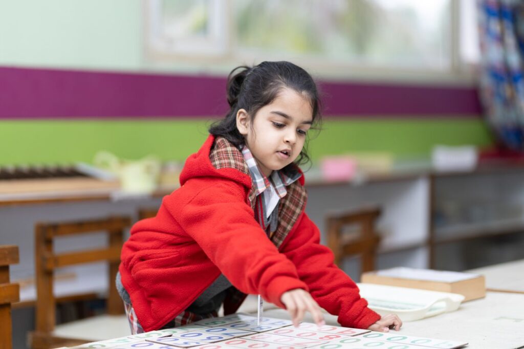 A young girl engages with educational materials in a vibrant classroom setting, promoting early learning.