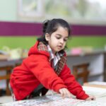 A young girl engages with educational materials in a vibrant classroom setting, promoting early learning.