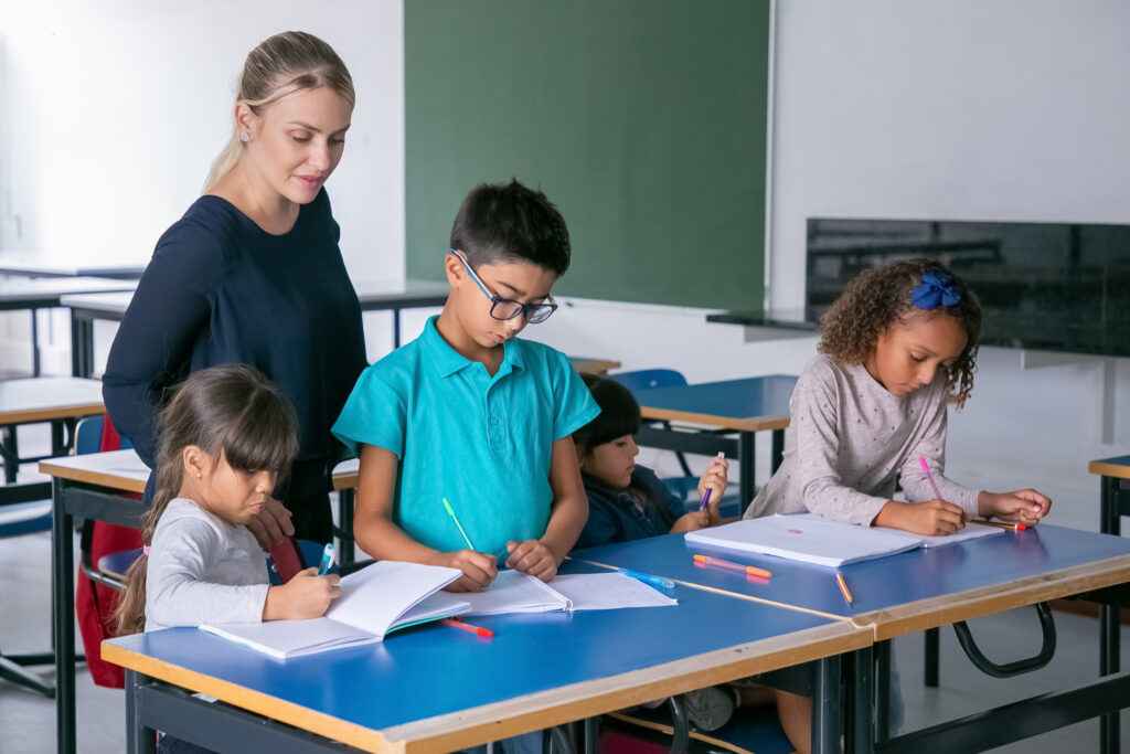 positive female school teacher watching kids doing their task